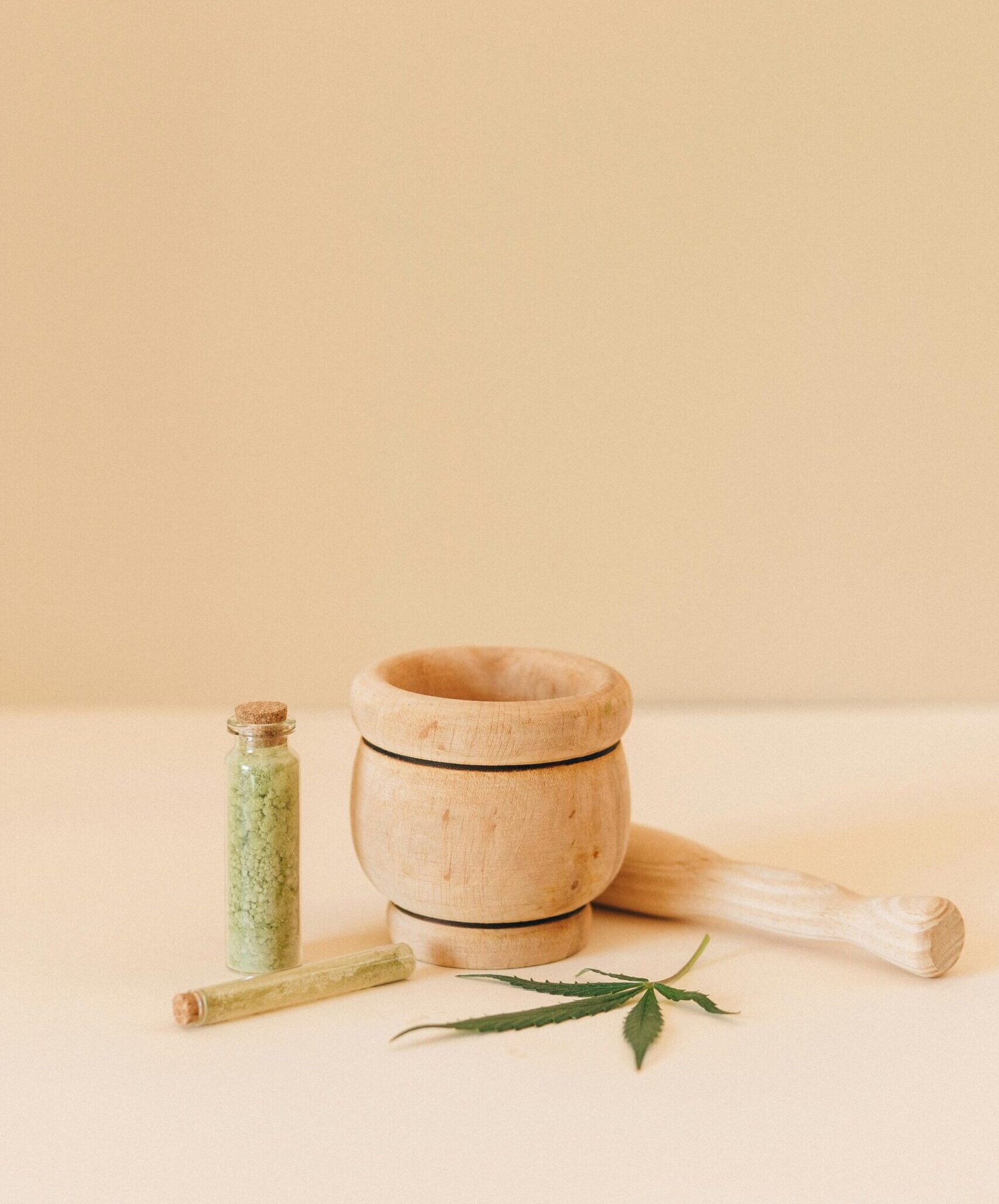Aesthetic setup of herbal remedy tools with a mortar, pestle, and cannabis leaf.